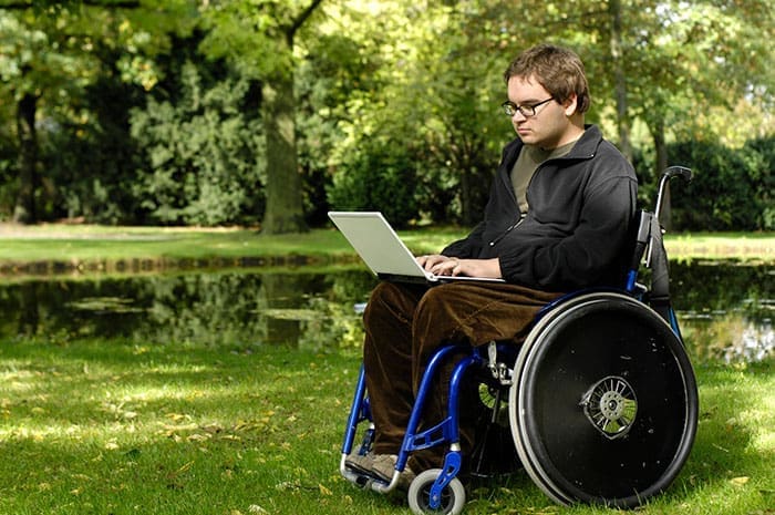 man in wheelchair reading laptop