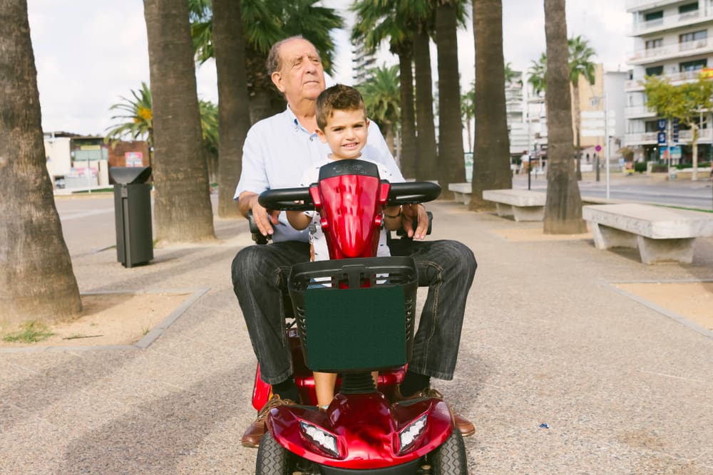 Grandfather and grandson with a electric wheelchair on vacation
