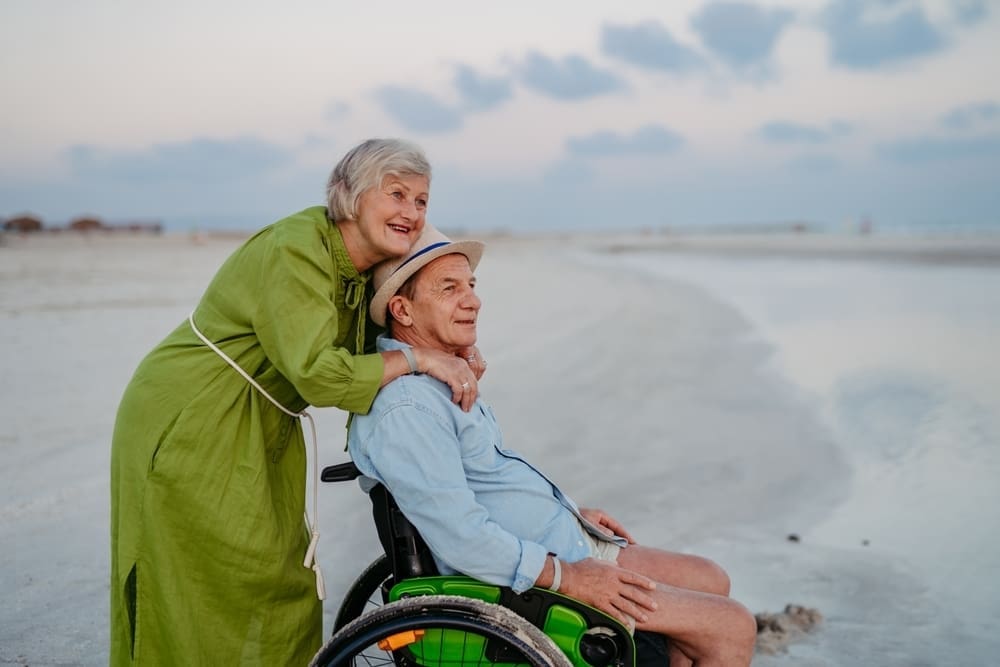Senior man on wheelchair enjoying together time with his wife at sea.